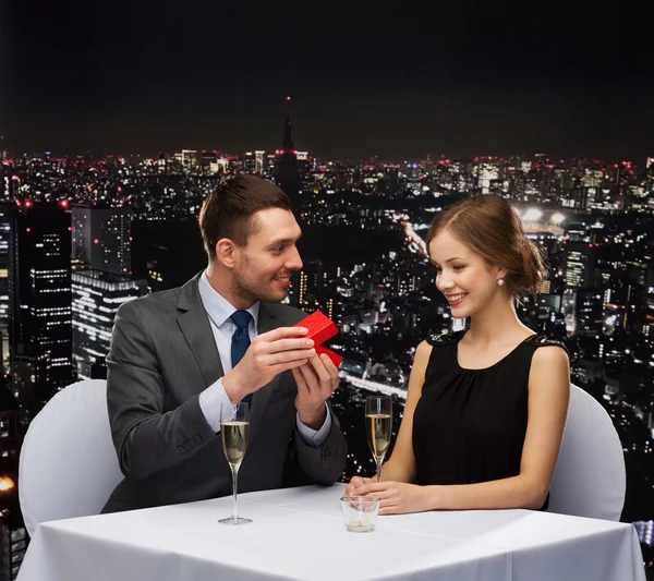 Excited young woman looking at boyfriend with box — Stock Photo, Image