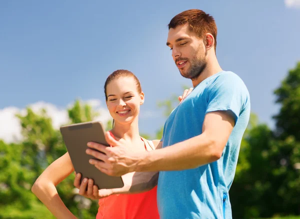 Lachende paar met tablet pc buitenshuis — Stockfoto