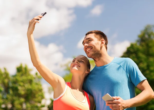 Duas pessoas sorridentes com smartphones ao ar livre — Fotografia de Stock