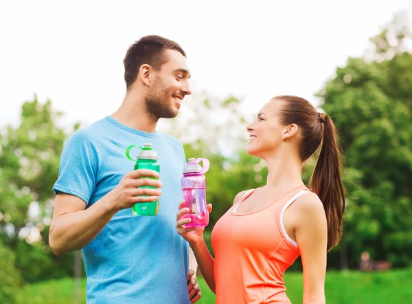 Couple souriant avec des bouteilles d'eau à l'extérieur — Photo