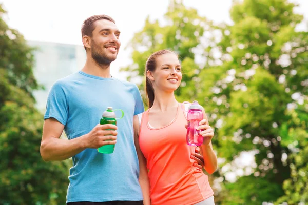 Smiling couple with bottles of water outdoors — Stock Photo, Image