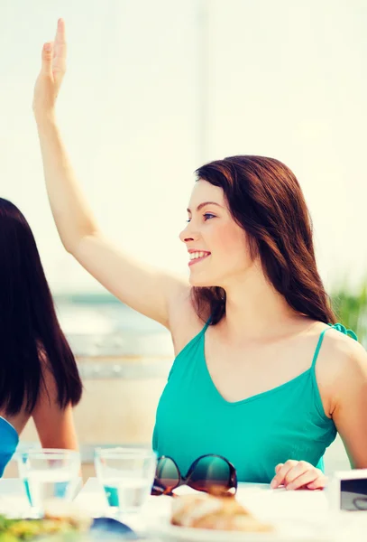 Girl waving hand in cafe on the beach — Stock Photo, Image