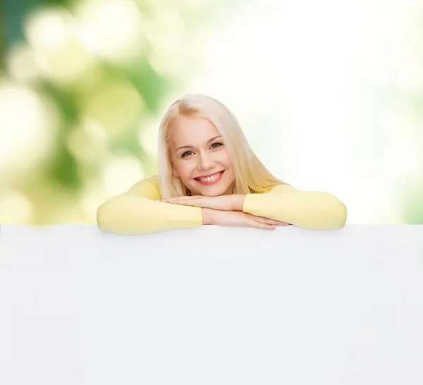 Mulher sorridente em suéter com placa branca em branco — Fotografia de Stock