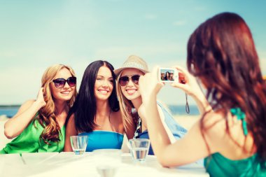 girls taking photo in cafe on the beach clipart