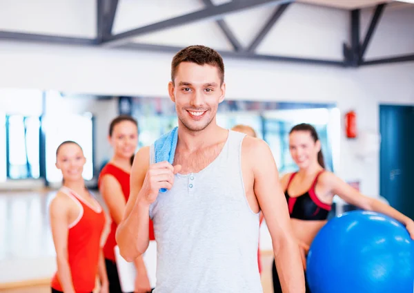 Uomo sorridente in piedi davanti al gruppo in palestra — Foto Stock