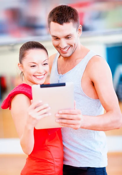 Twee lachende mensen met tablet pc in de sportschool — Stockfoto