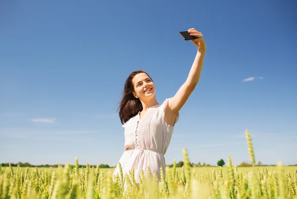 Smiling girl with smartphone on cereal field — Stock Photo, Image