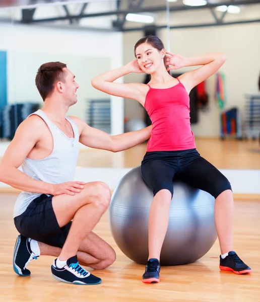 Male trainer with woman doing crunches on the ball Royalty Free Stock Photos
