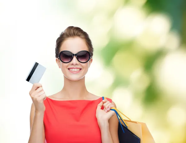 Glimlachende vrouw met boodschappentassen en plastic kaart — Stockfoto