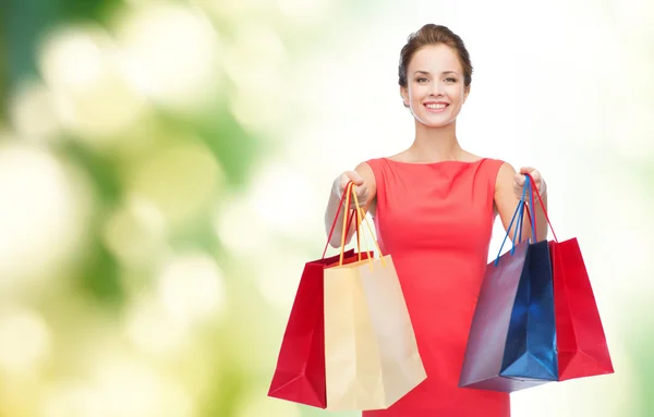 Lachende elegante vrouw in jurk met shopping tassen — Stockfoto