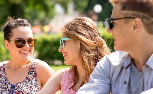 Grupo de amigos sorridentes ao ar livre sentado no parque — Fotografia de Stock