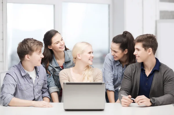 Lachende studenten met laptop op school — Stockfoto