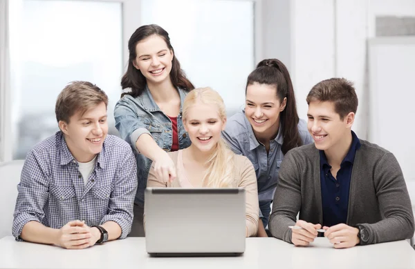 Lachende studenten kijken naar laptop op school — Stockfoto