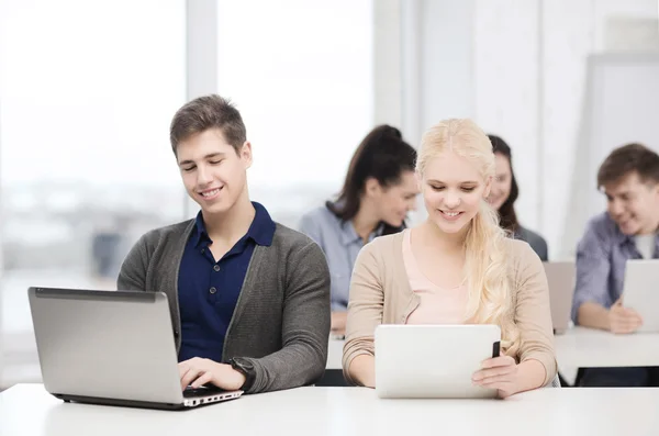 Twee lachende studenten met laptop en tablet pc — Stockfoto