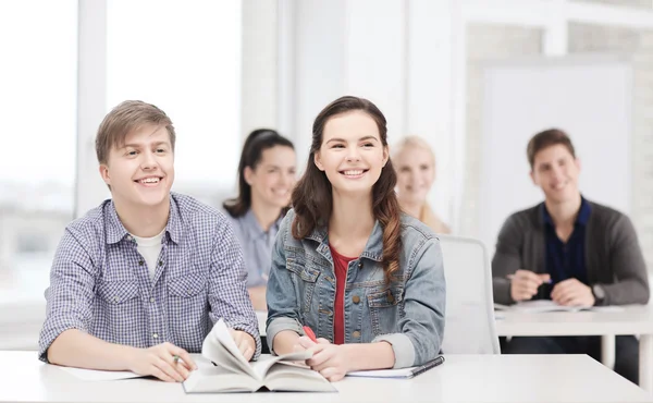 Dos adolescentes con cuadernos y libro en la escuela — Foto de Stock