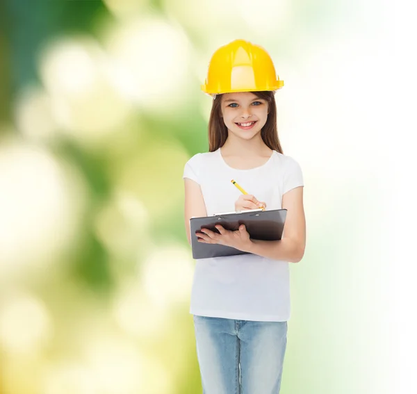 Petite fille souriante en hardhat avec presse-papiers — Photo