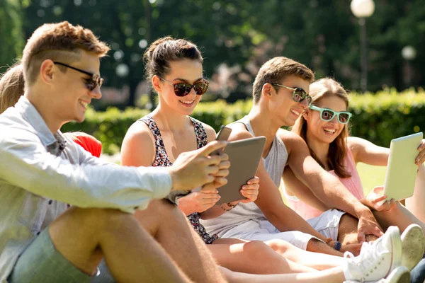 Sorridendo gli amici con computer pc tablet nel parco — Zdjęcie stockowe