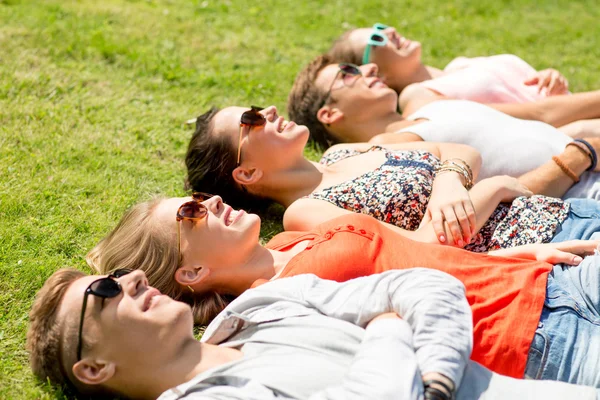 Grupo de amigos sonrientes tumbados en la hierba al aire libre —  Fotos de Stock