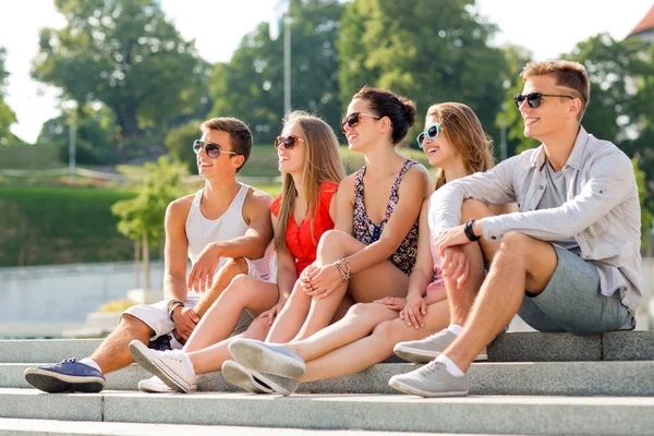 Grupp leende vänner sitter på torget — Stockfoto