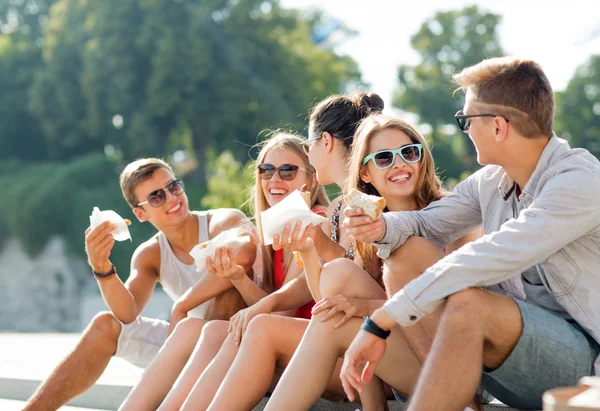 Group of smiling friends sitting on city square — Stock Photo, Image