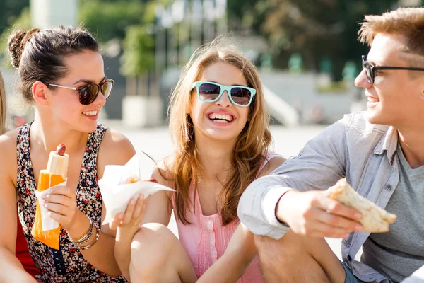 Grupo de amigos sorridentes sentados na praça da cidade — Fotografia de Stock