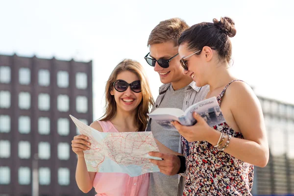 Lächelnde Freunde mit Karte und Stadtführer im Freien — Stockfoto