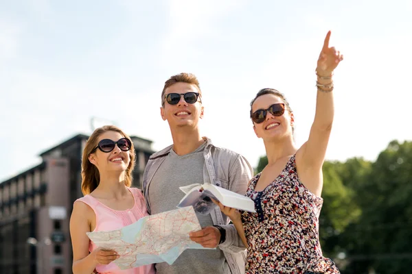 smiling friends with map and city guide outdoors