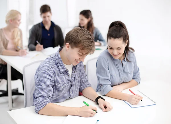 Usmívající se studenti s notebookem ve škole — Stock fotografie