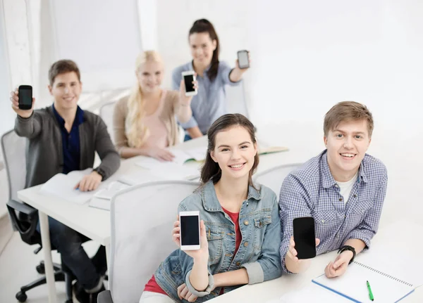 Studenti che mostrano schermi bianchi neri dello smartphone — Foto Stock