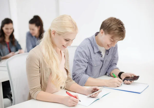 Lachende studenten met laptops op school — Stockfoto