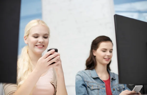 Dois adolescentes com smartphones em classe de computador — Fotografia de Stock