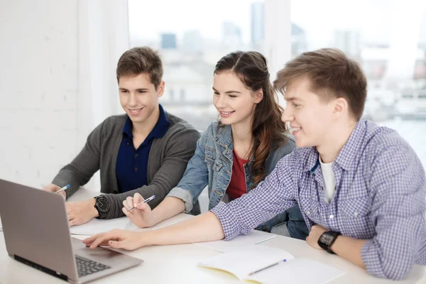 Tre leende studenter med bärbar dator och bärbara datorer — Stockfoto