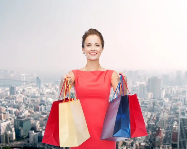 Lachende elegante vrouw in jurk met shopping tassen — Stockfoto