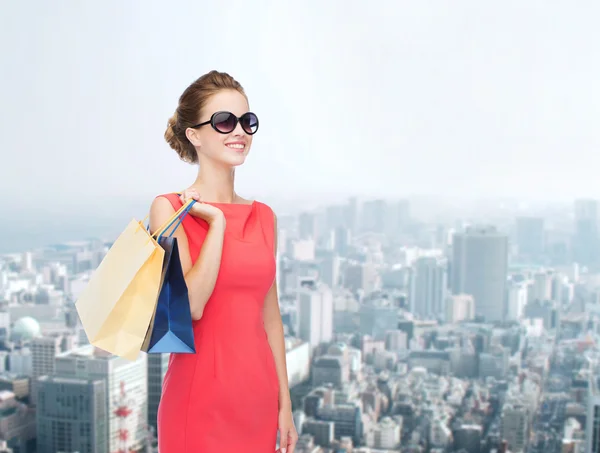 Улыбающаяся элегантная женщина в платье с сумками для покупок — стоковое фото