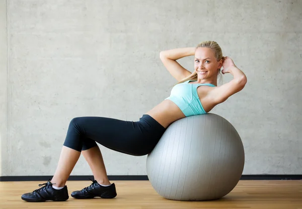 Mujer sonriente con pelota de ejercicio en el gimnasio — Foto de Stock