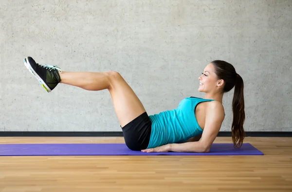 Улыбающаяся женщина делает упражнения на коврике в тренажерном зале — стоковое фото
