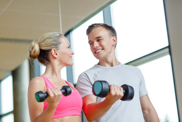 Glimlachende jonge vrouw met personal trainer in de sportschool — Stockfoto