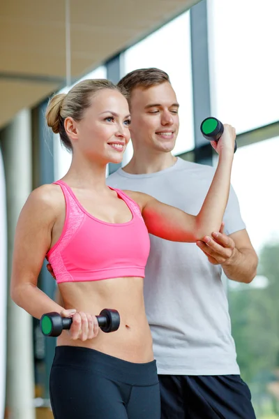 Smiling young woman with personal trainer in gym Stock Picture