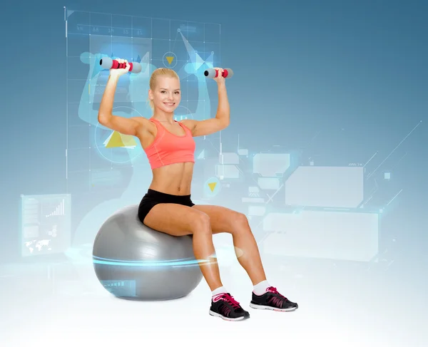 Woman with dumbbells sitting on fitness ball — Stock Photo, Image