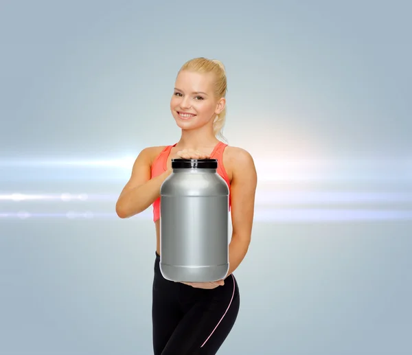 Mujer deportiva sonriente con tarro de proteína — Foto de Stock