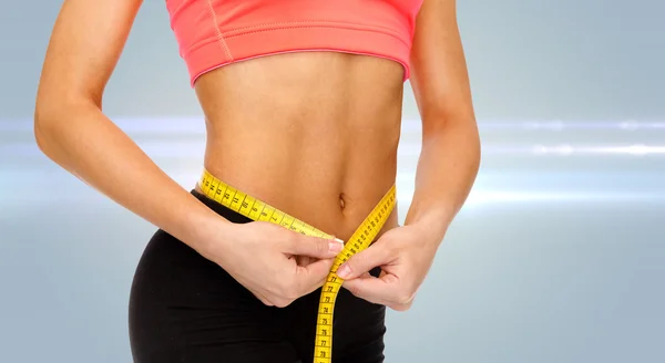 Close up of female hands measuring waist — Stock Photo, Image