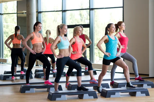 Grupo de mujeres haciendo ejercicio con los pasos en el gimnasio — Foto de Stock