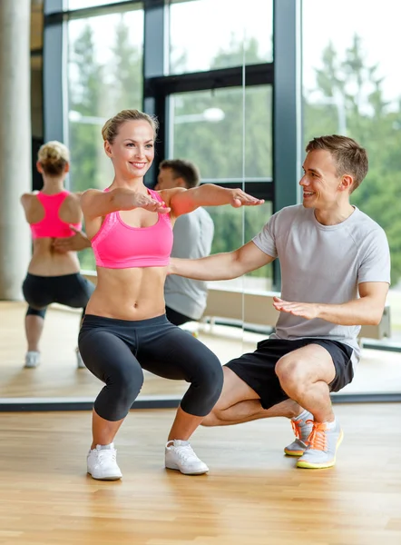 Lachende vrouw met mannelijke trainer trainen in de sportschool — Stockfoto