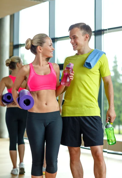 Lachende paar met water flessen in gym — Stockfoto