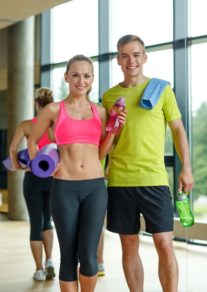 Coppia sorridente con borracce in palestra — Foto Stock