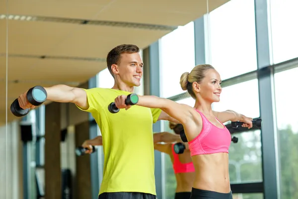 Smiling man and woman with dumbbells in gym — Stock Photo, Image