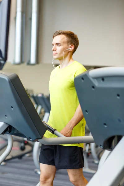 Man met smartphone uitoefenen op loopband in de sportschool — Stockfoto