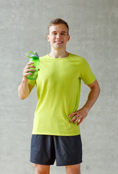 Hombre sonriente con botella de agua en el gimnasio —  Fotos de Stock