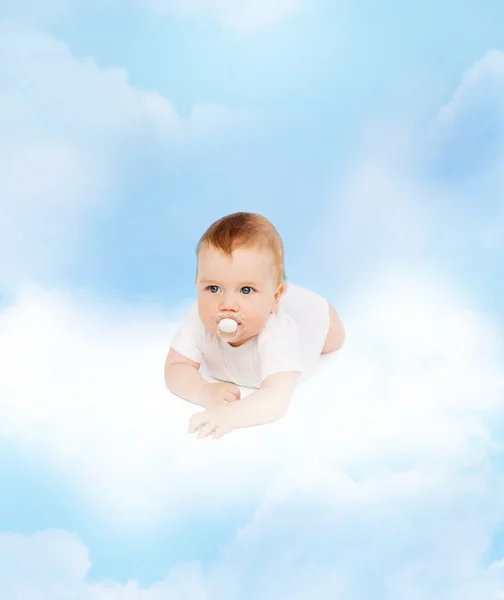 Lächelndes Baby auf Wolke liegend mit Schnuller im Mund — Stockfoto