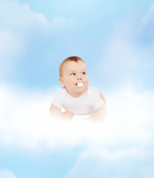 Sonriente bebé acostado en la nube con maniquí en la boca — Foto de Stock